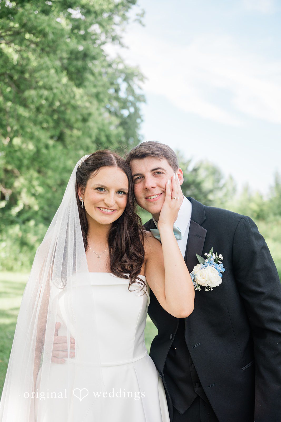 Paige + Stephen A smiling bride in a white gown standing next to a groom in a black suit.