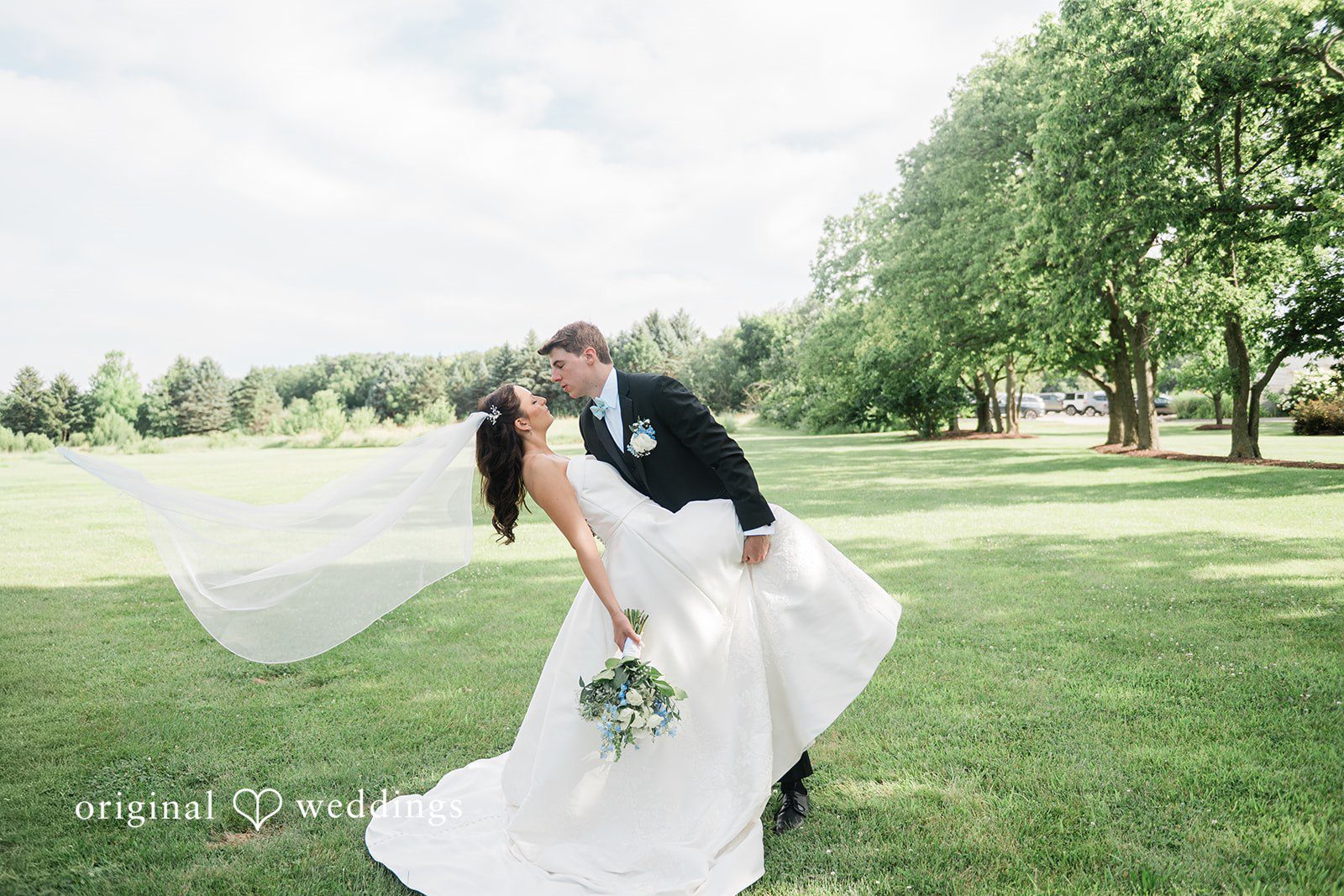 Paige + Stephen A bride with a long veil walking gracefully across an open green lawn.