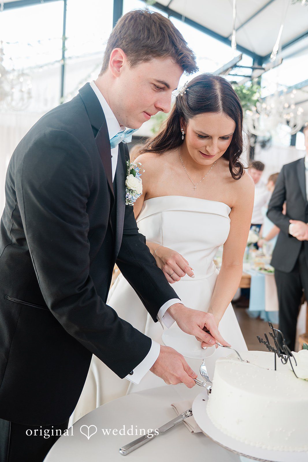 Paige + Stephen A bride and groom standing together while cutting their tiered wedding cake.