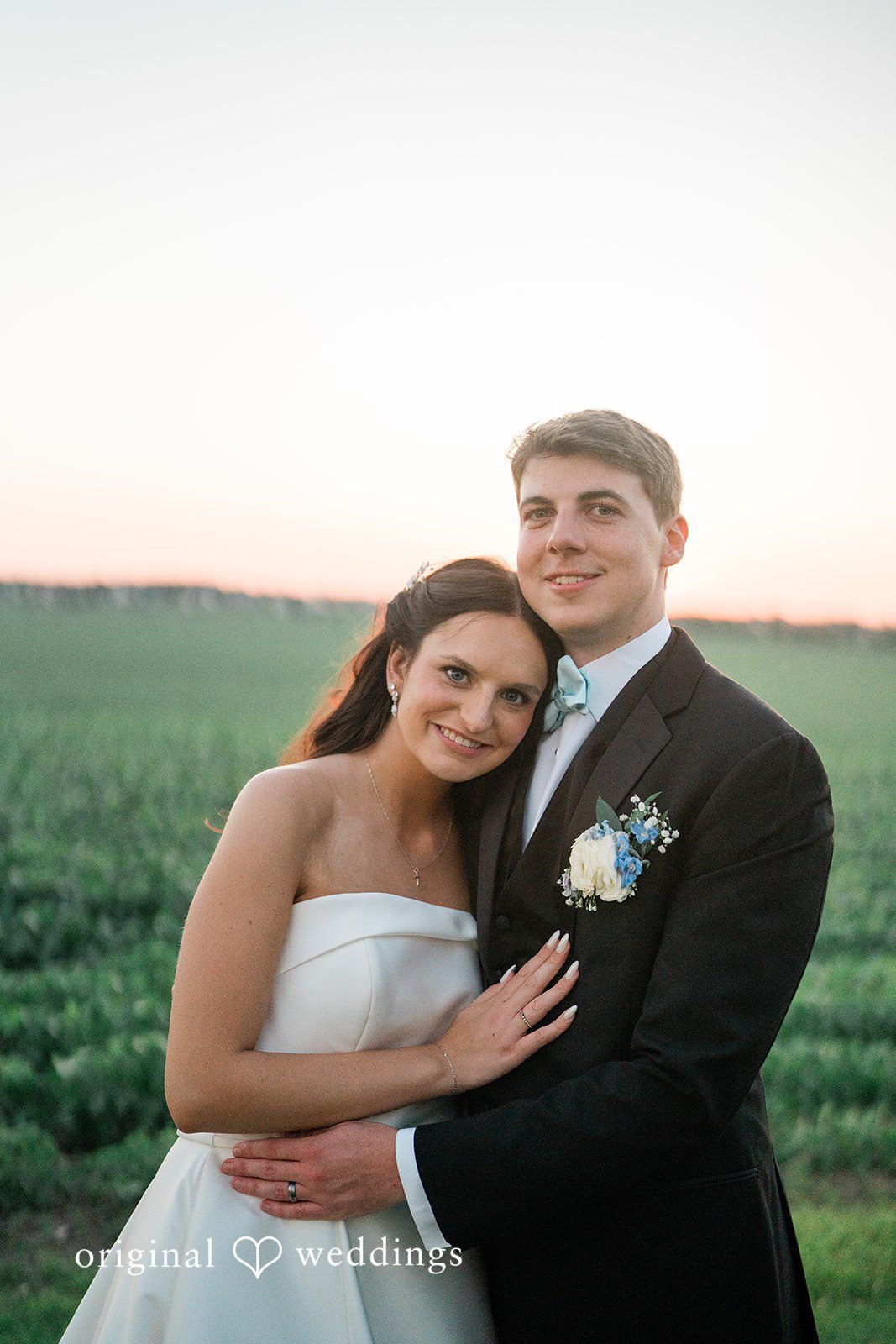 Paige + Stephen A groom holding a bride close as they share a moment in a sunny field.