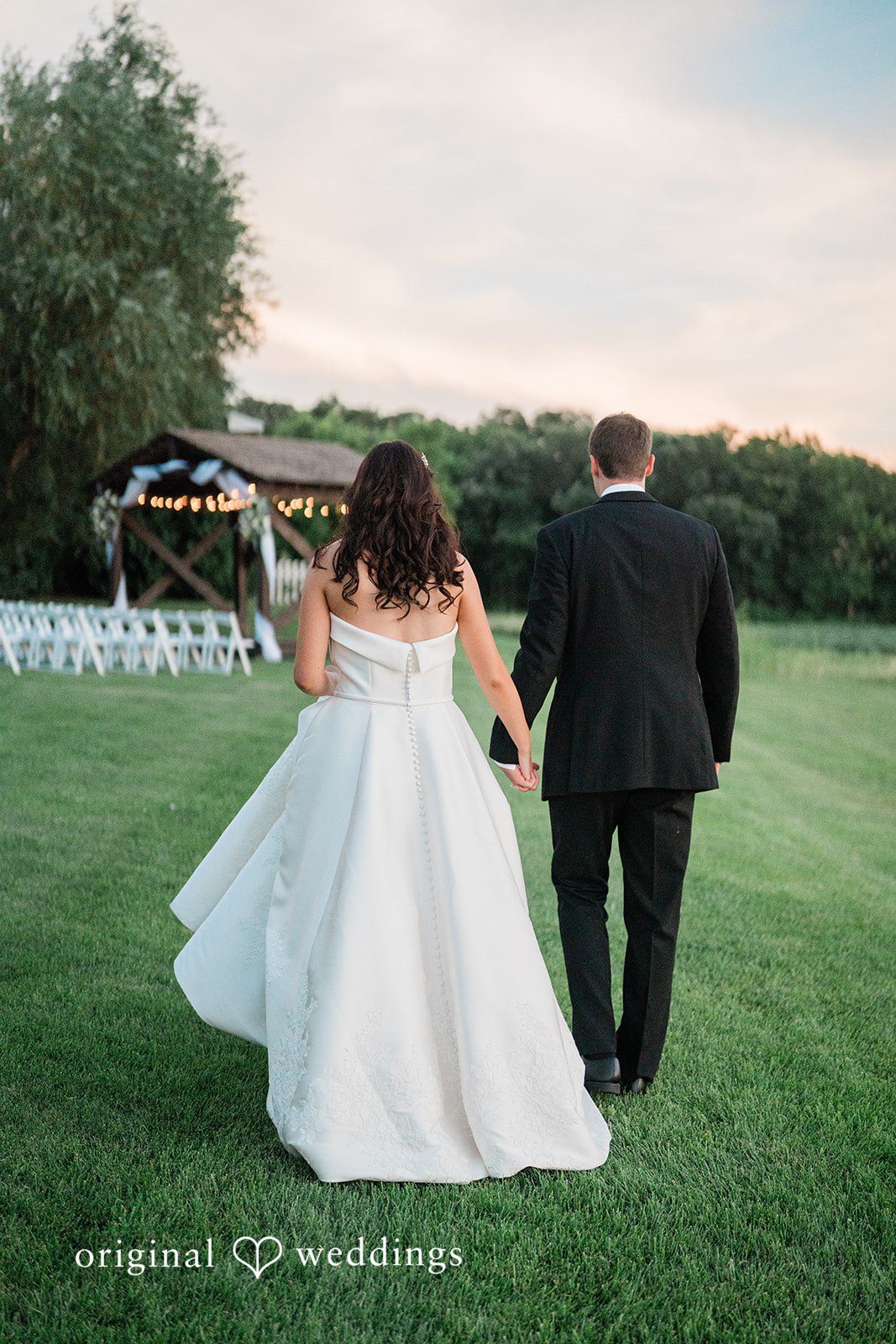 Paige + Stephen A bride in a white gown walking through a wide, open grassy area.