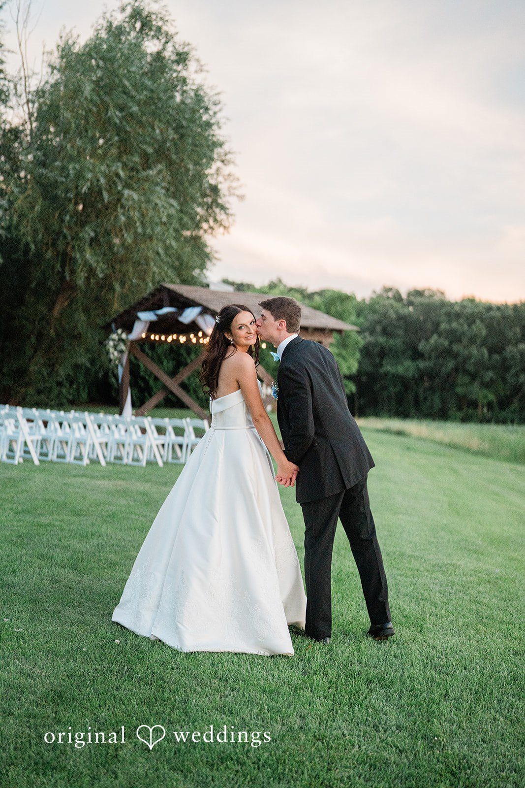 Paige + Stephen A bride and groom standing together in a field at sunset during their wedding portraits.