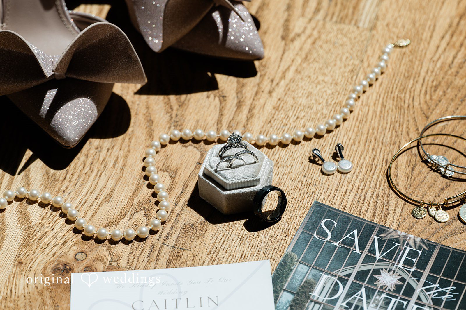 A top-down view of bridal jewelry, perfume, and custom stationery spread across a wooden surface.