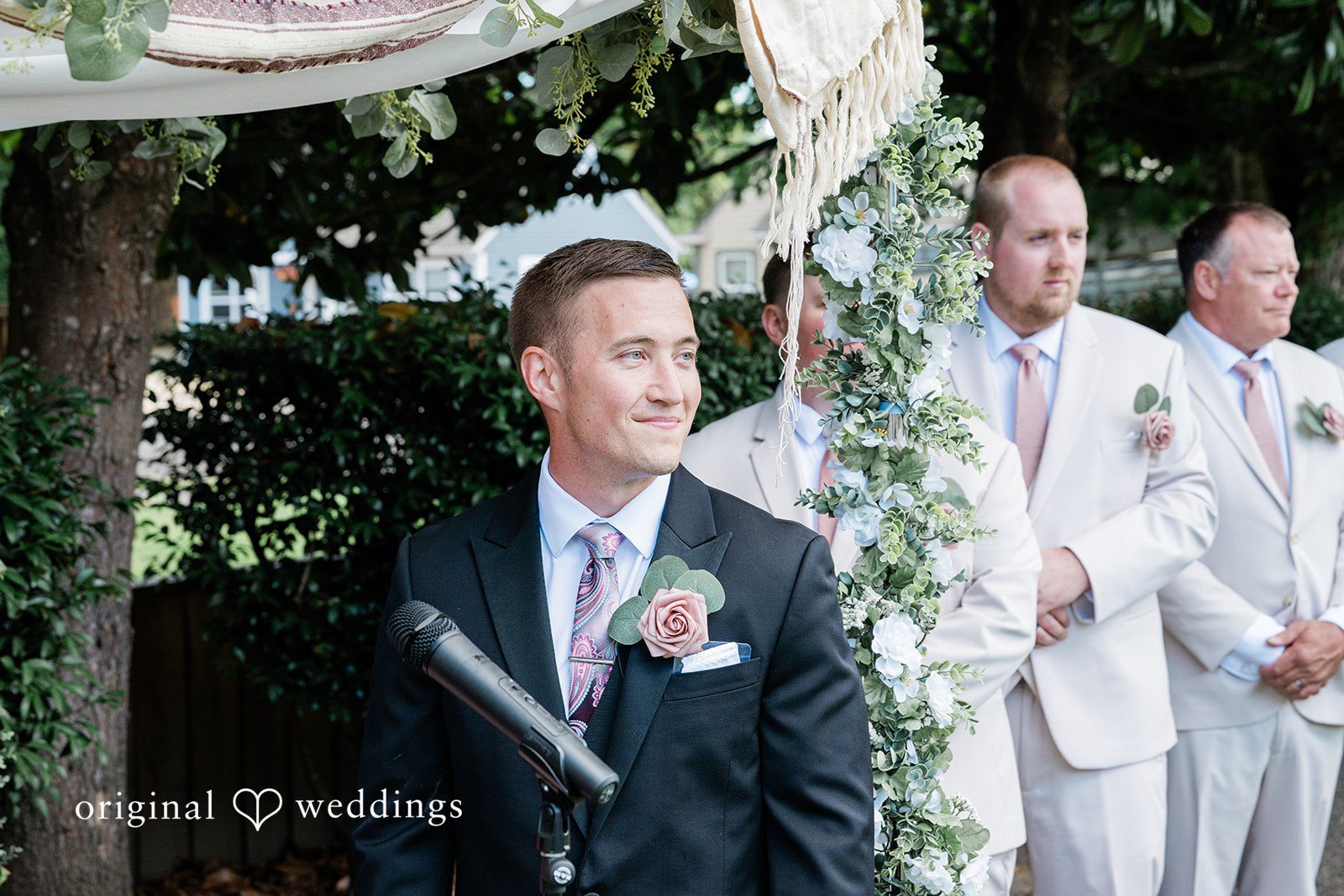 A groom smiling happily as he stands at the altar waiting for his bride.