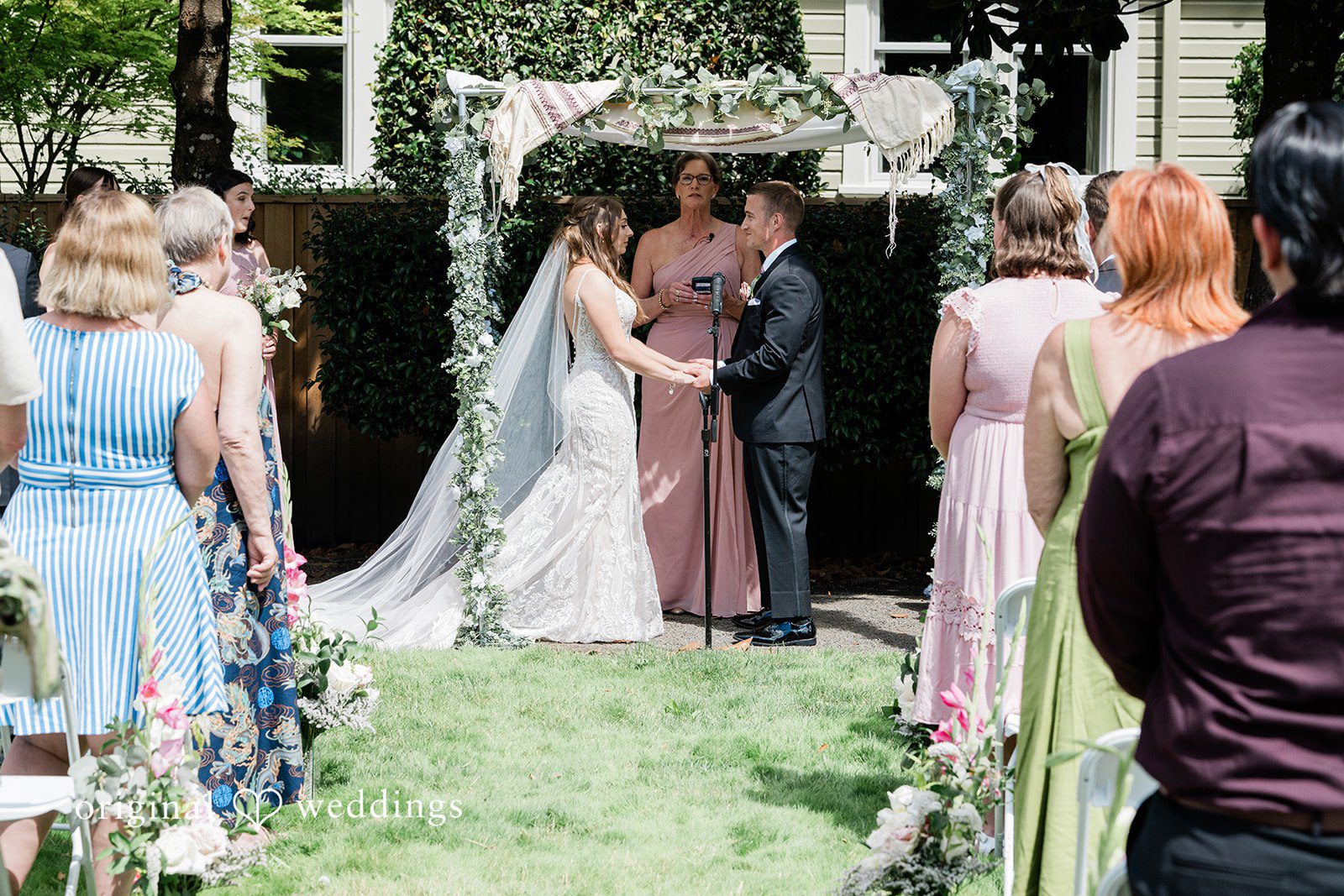 A bride walking down a grassy wedding aisle towards her groom.