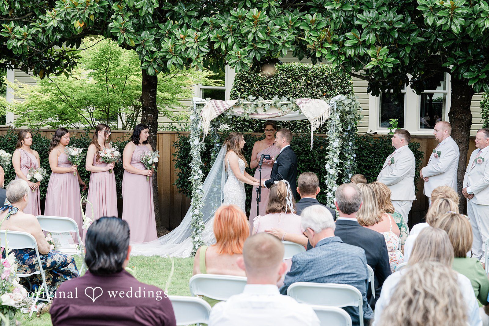 A view from behind the guests watching a bride and groom during their wedding ceremony.