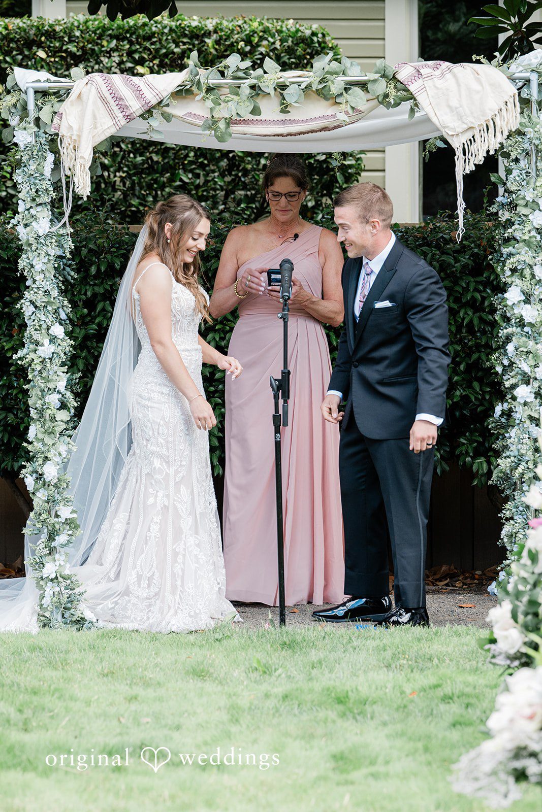 A wedding ceremony in progress with the bride, groom, and an officiant holding a book.
