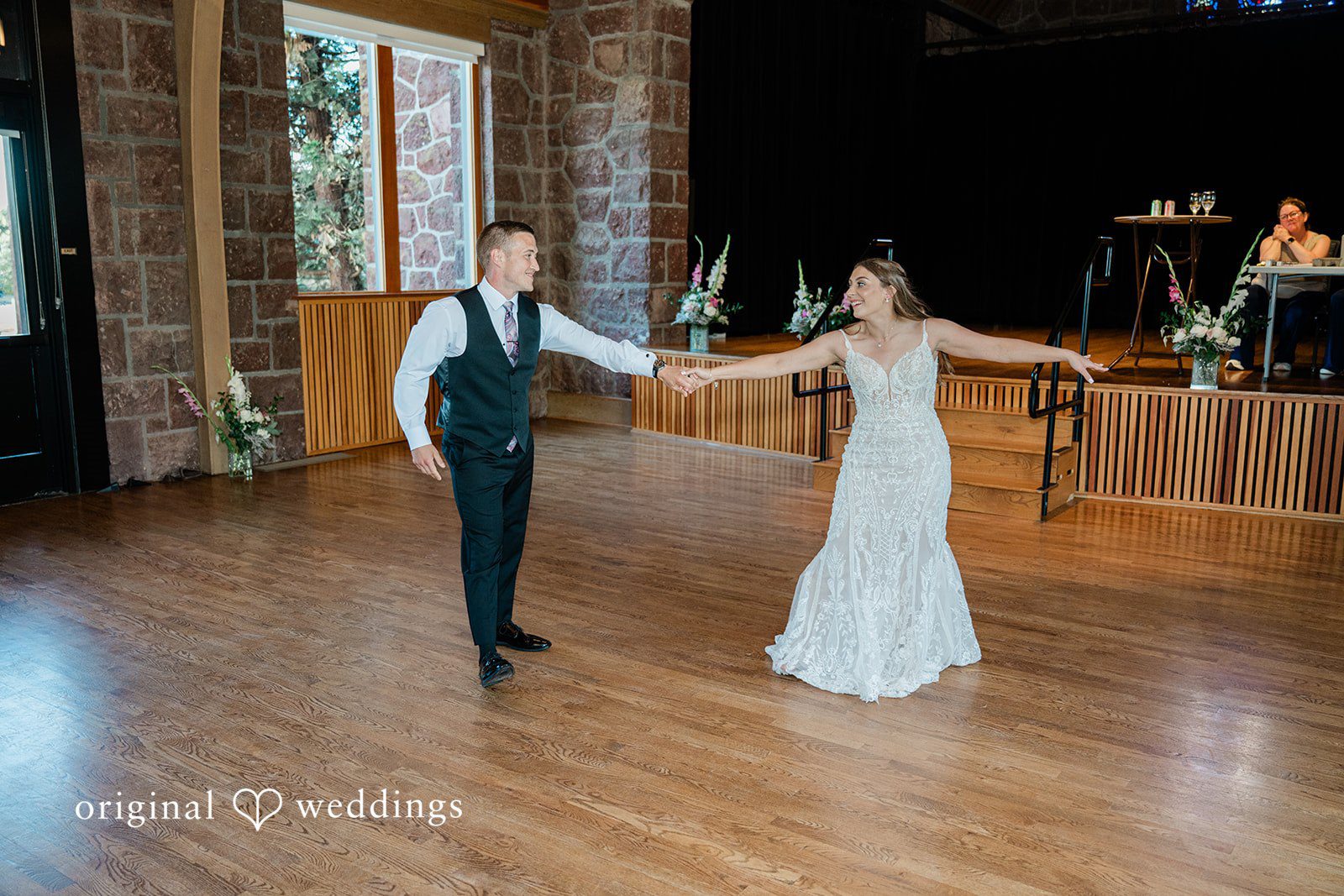 A bride and groom sharing their first dance together on a polished wooden dance floor.