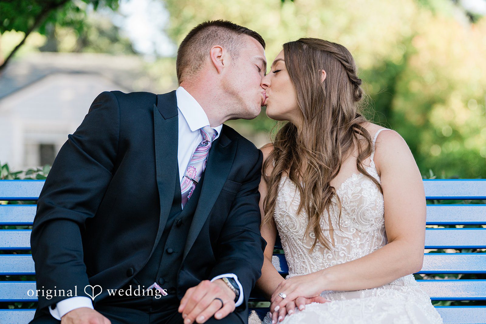 A close-up portrait of a bride and groom kissing at each other.