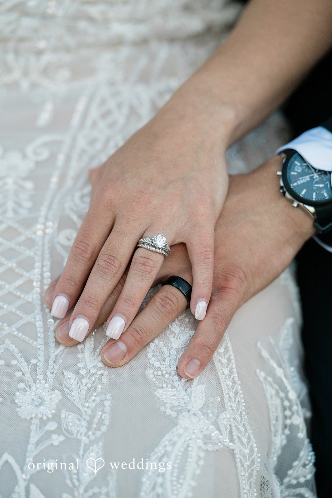 A close-up of a bride and groom holding hands, showcasing the wedding ring on her finger.