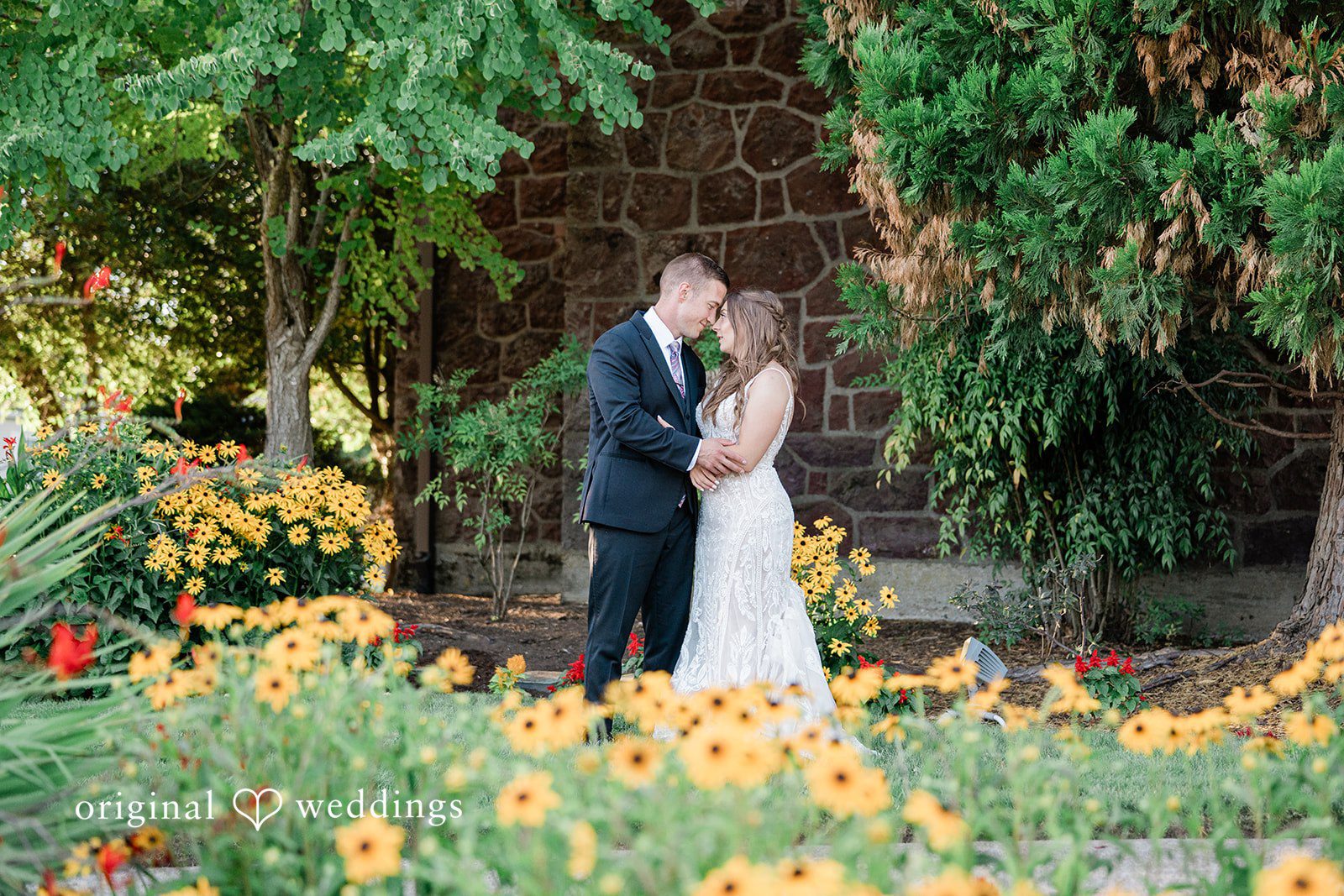 A bride and groom sharing a quiet moment together in a field of bright yellow flowers.