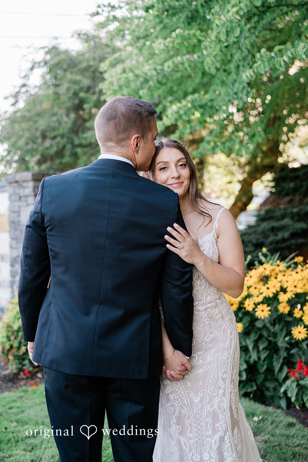 A bride resting her hands on the groom's shoulders while looking at him lovingly.
