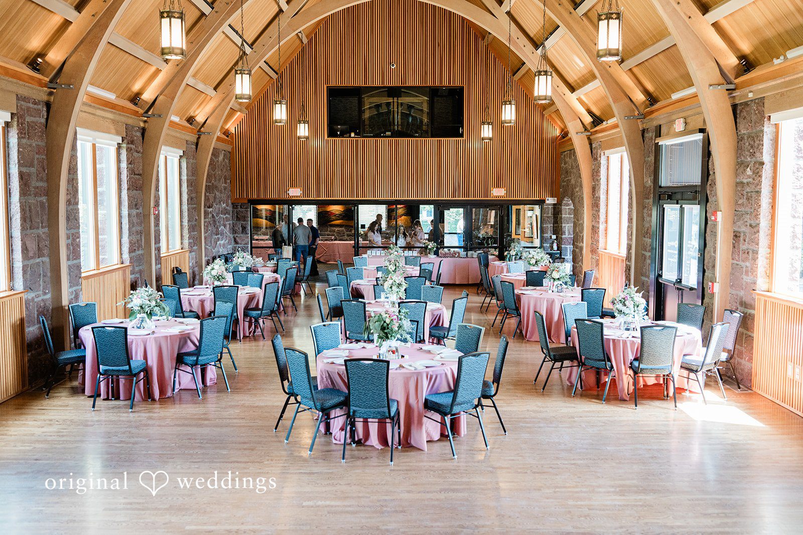 A large banquet hall filled with round tables dressed in bright teal tablecloths.