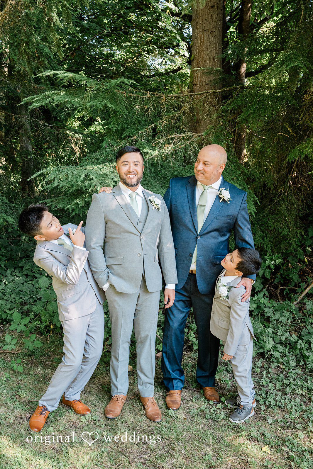 Harley + Mei Four men in formal attire standing and posing together under the trees.
