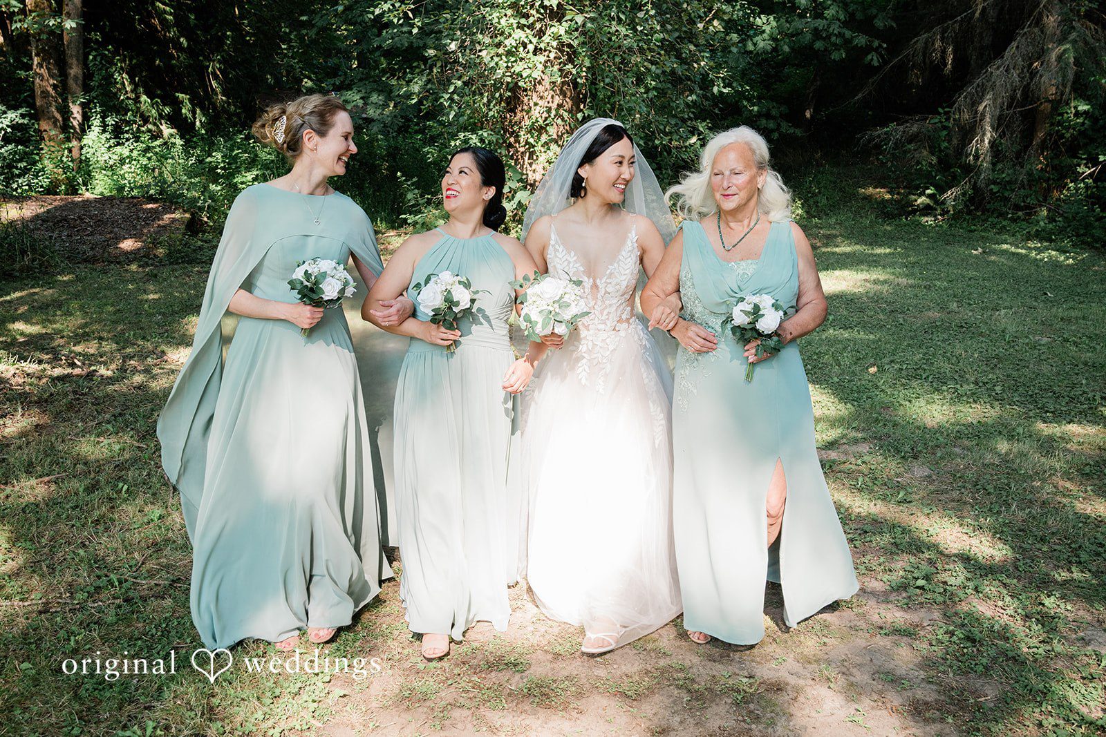 Harley + Mei Four bridesmaids in light blue dresses standing together in a park.