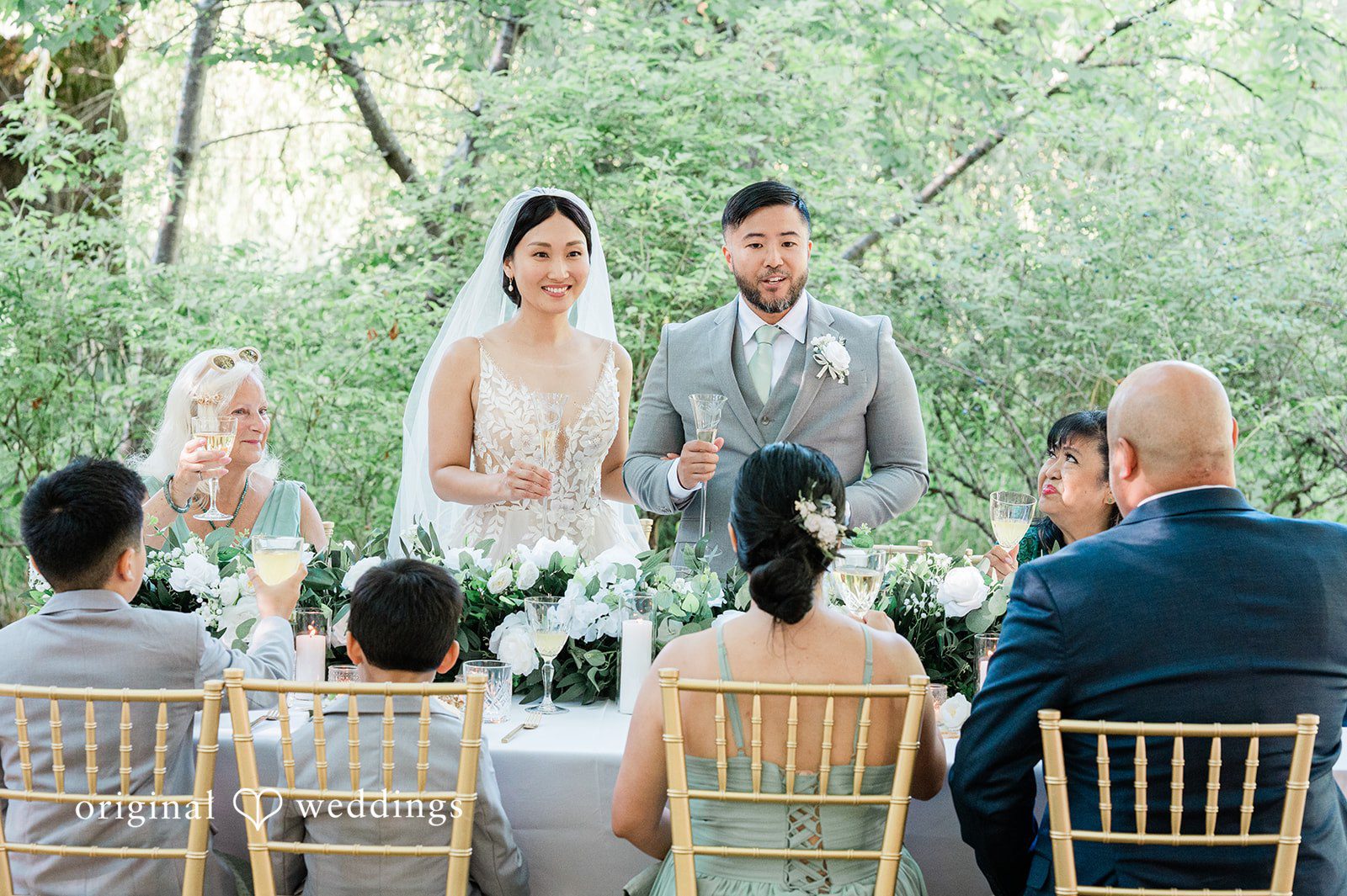 Harley + Mei A wedding party sitting at a table during a reception under a tent.