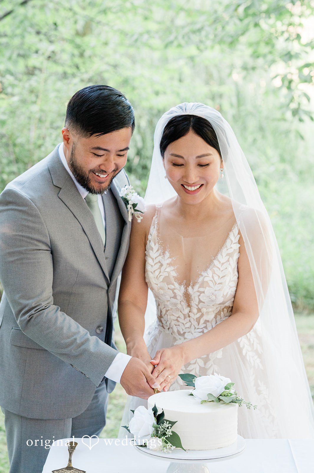 Harley + Mei A bride and groom smiling together behind a white wedding cake.