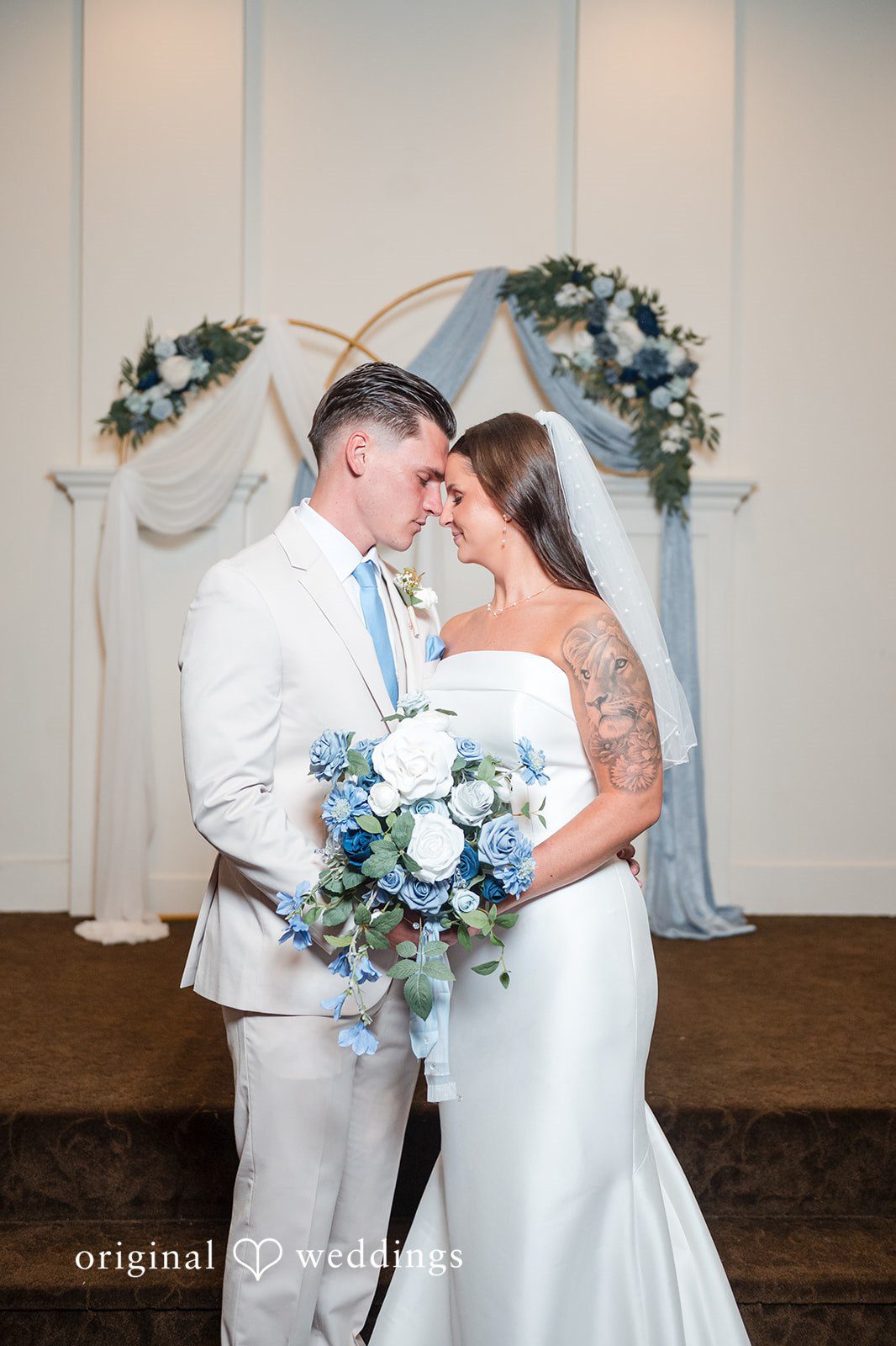 Jaclyn + Mason Bride and groom embracing and holding a blue bouquet.