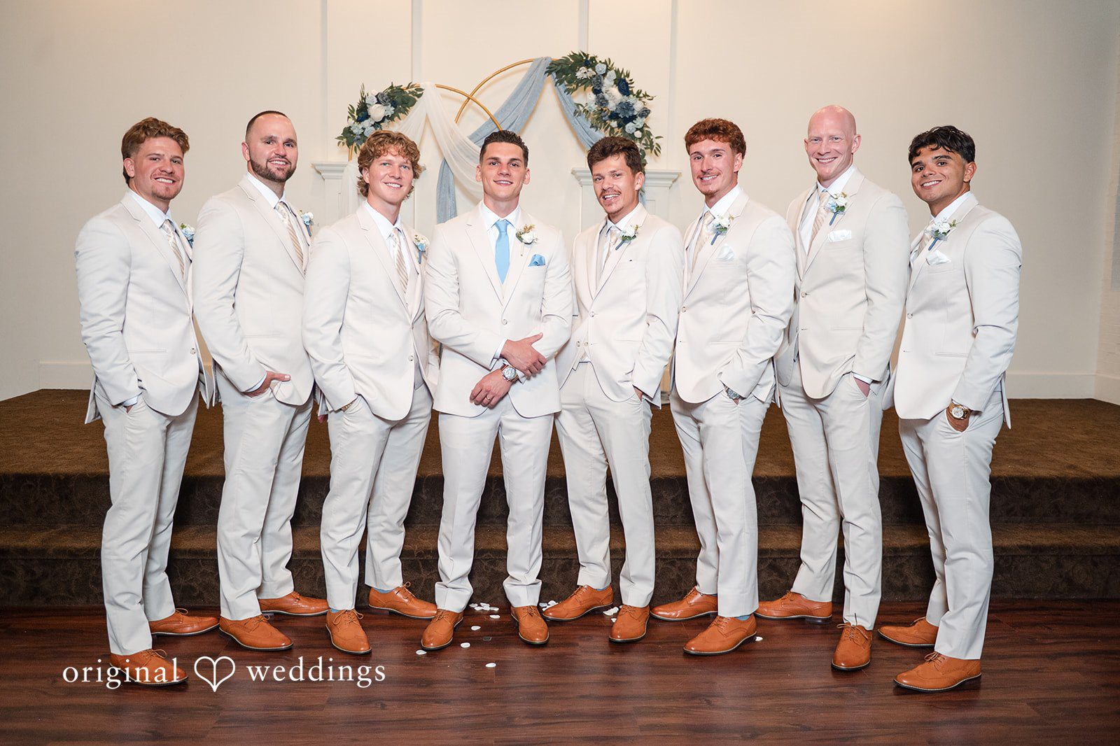 Jaclyn + Mason Groom posing with groomsmen all dressed in white suits.