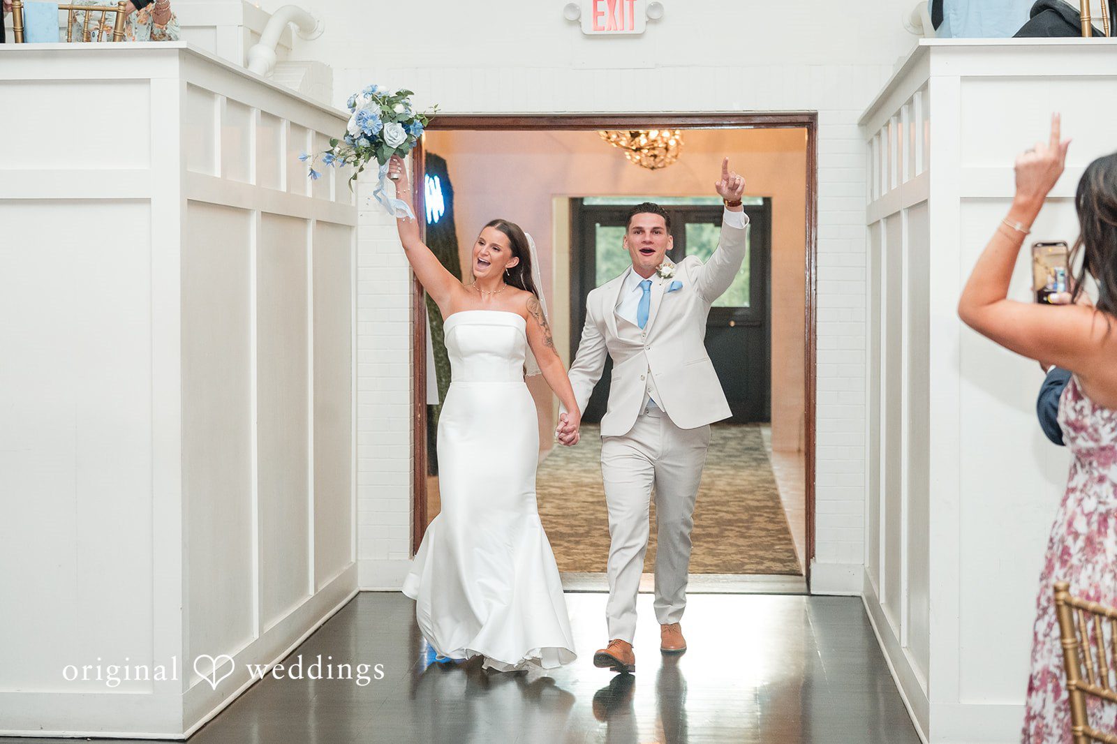 Jaclyn + Mason Bride waving as she walks through a doorway with the groom.