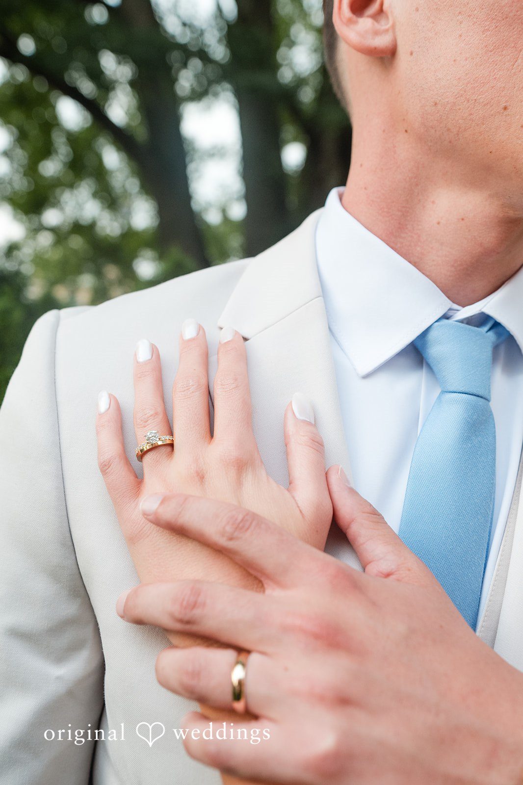 Jaclyn + Mason Close-up of a groom wearing a ring holding the bride's hand.