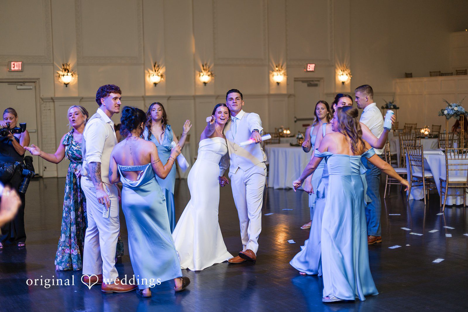 Jaclyn + Mason Group of wedding guests dancing under overhead lighting.