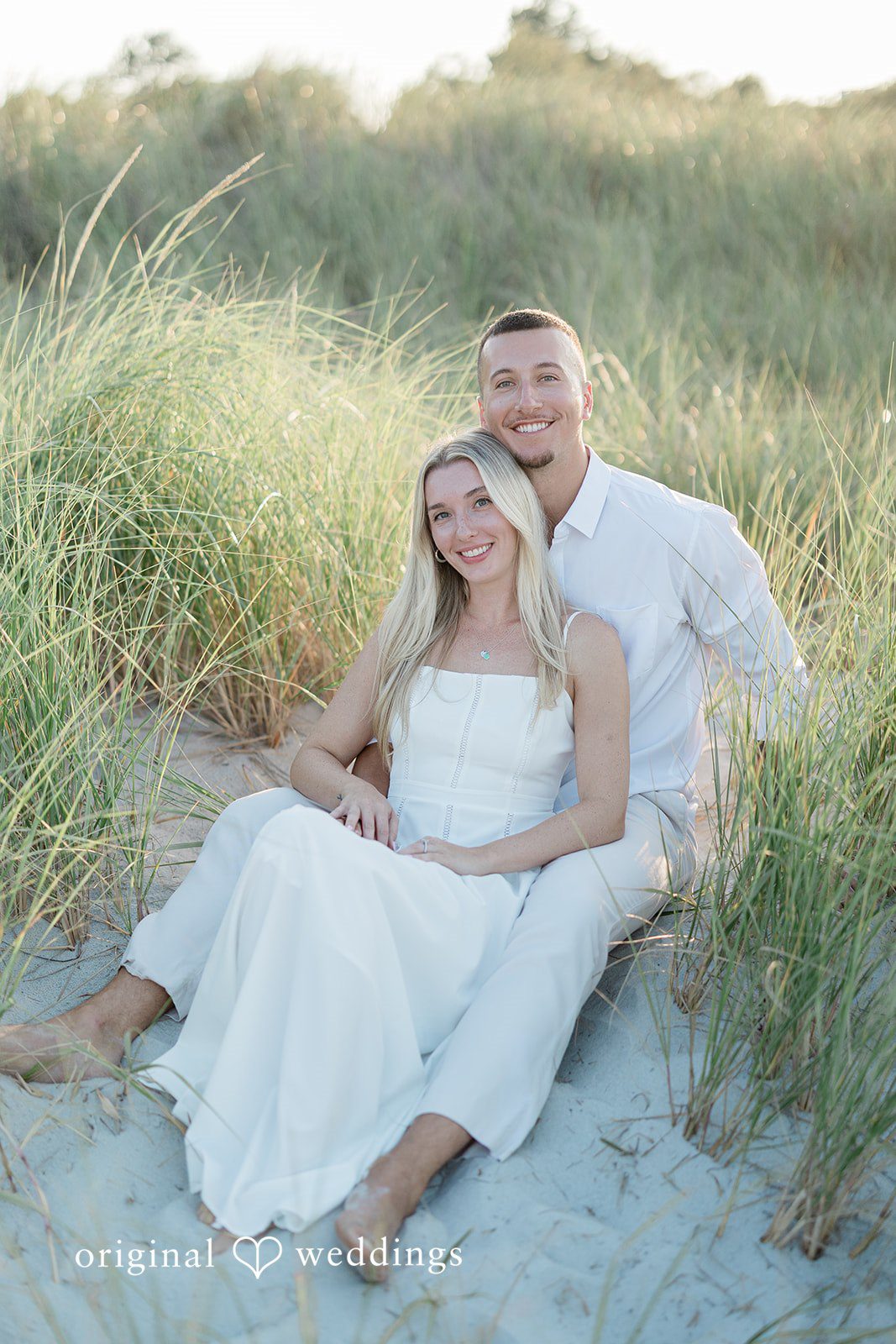 A couple sitting together and relaxing on a grassy hill.
