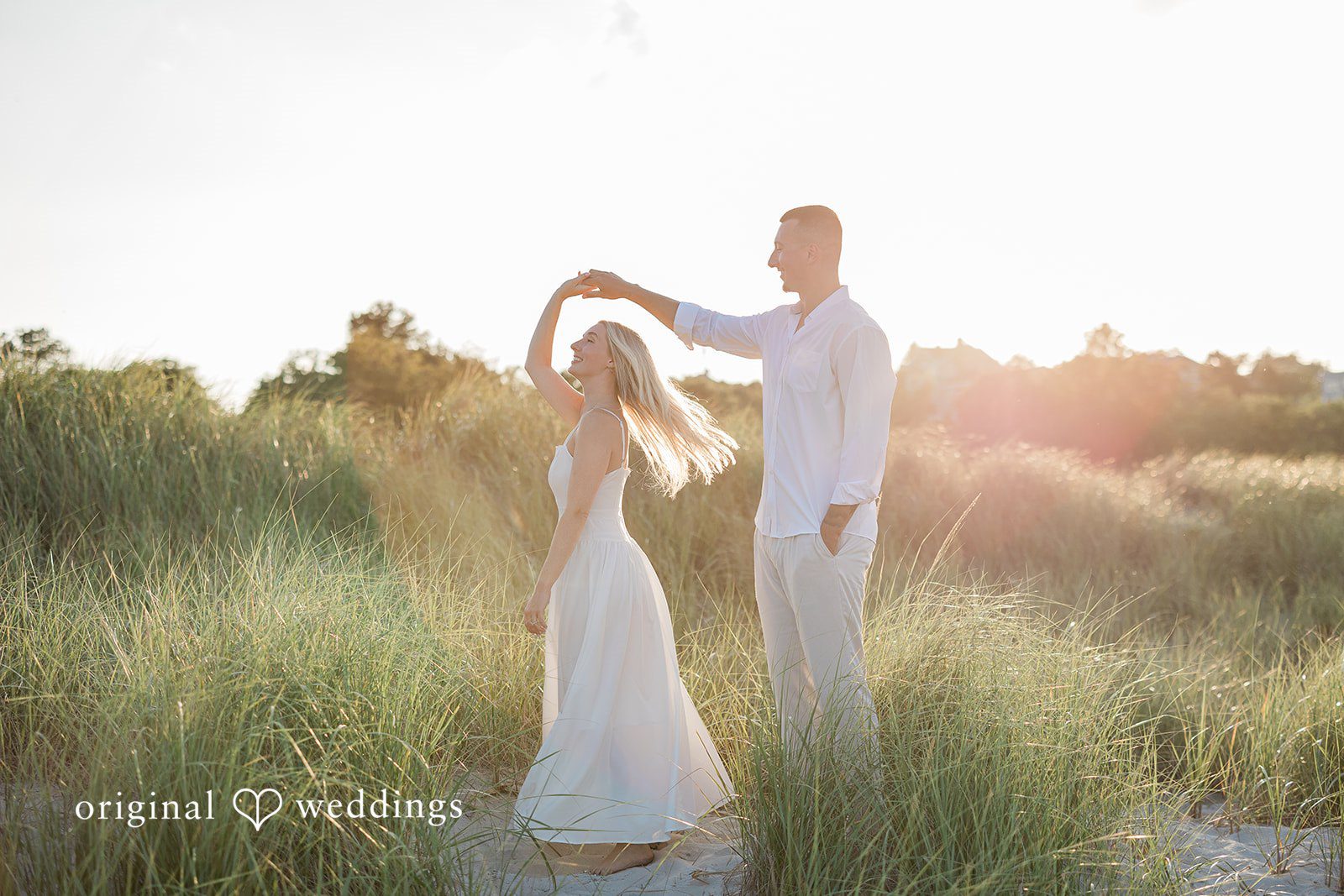 A couple dancing together in a field of tall grass.
