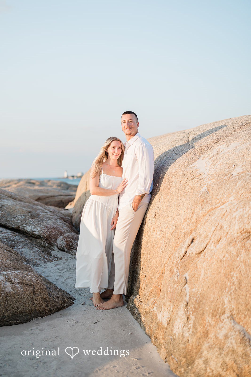 A couple standing together on a large rocky shoreline.