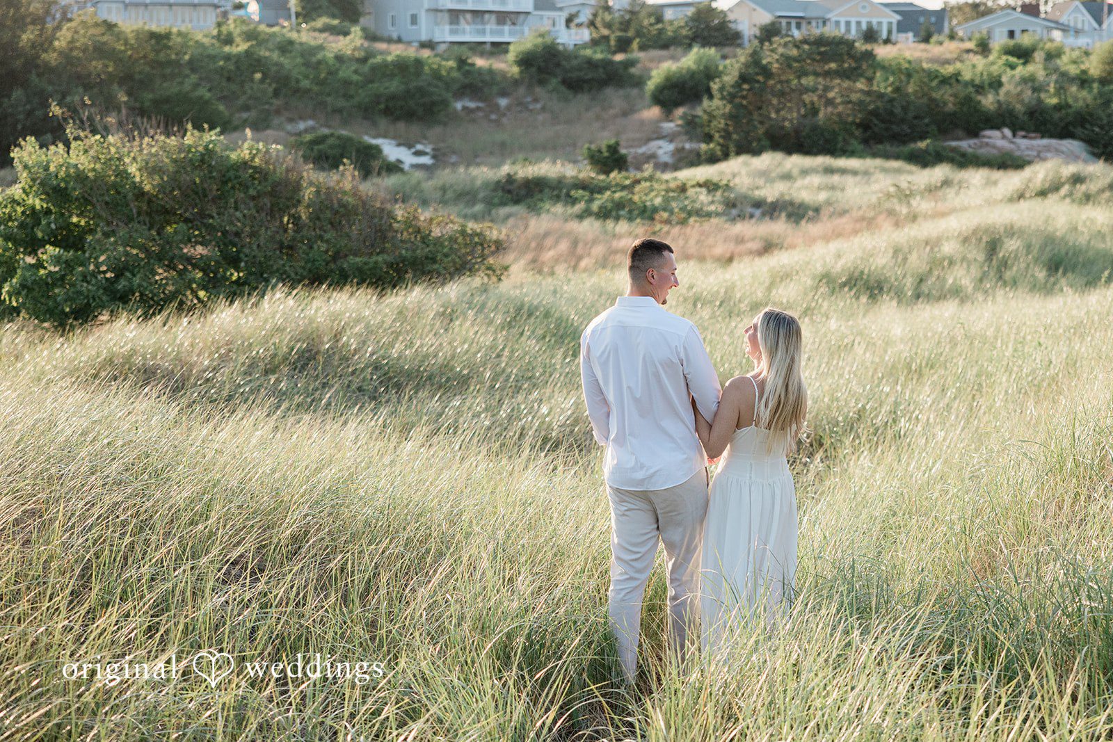 A distant shot of a couple walking together along a grassy pathway.