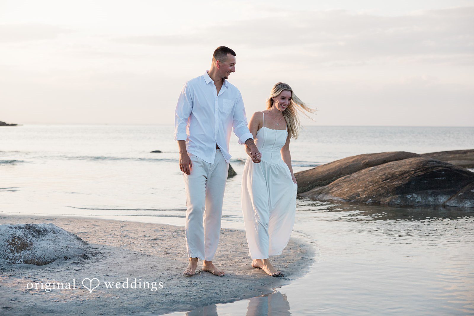 A couple walking next to each other on a rocky beach.