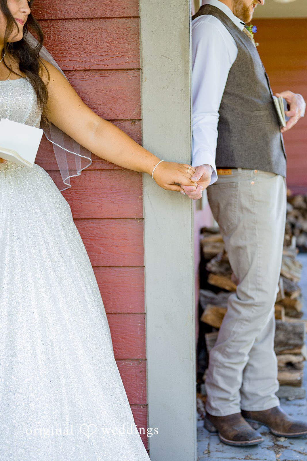 Melayna + Harley A bride holds hands with her groom as they stand near a building.