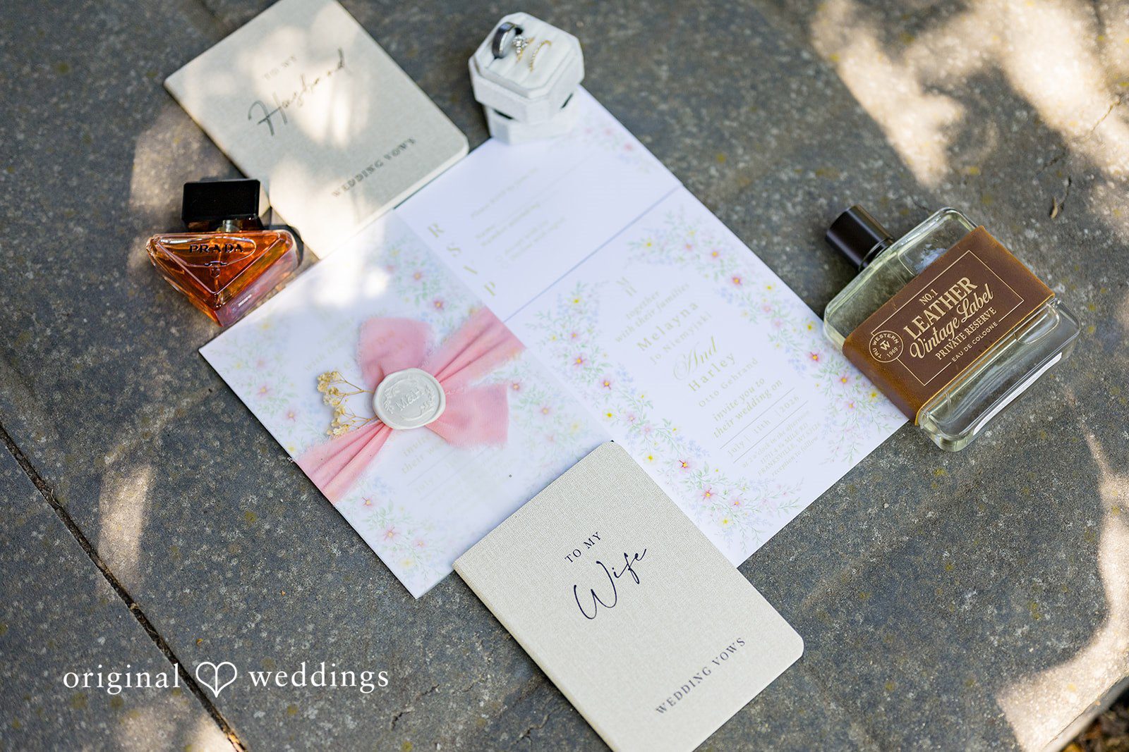 Melayna + Harley Wedding invitations and stationery are laid out on a wooden surface.