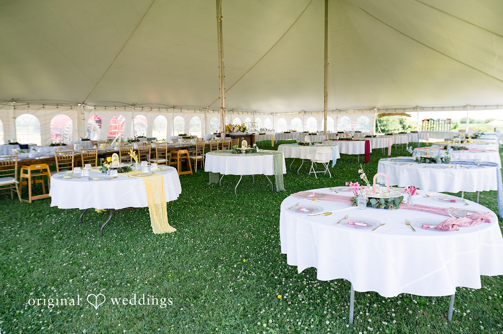 Melayna + Harley White tables and chairs are set up inside a large reception tent.