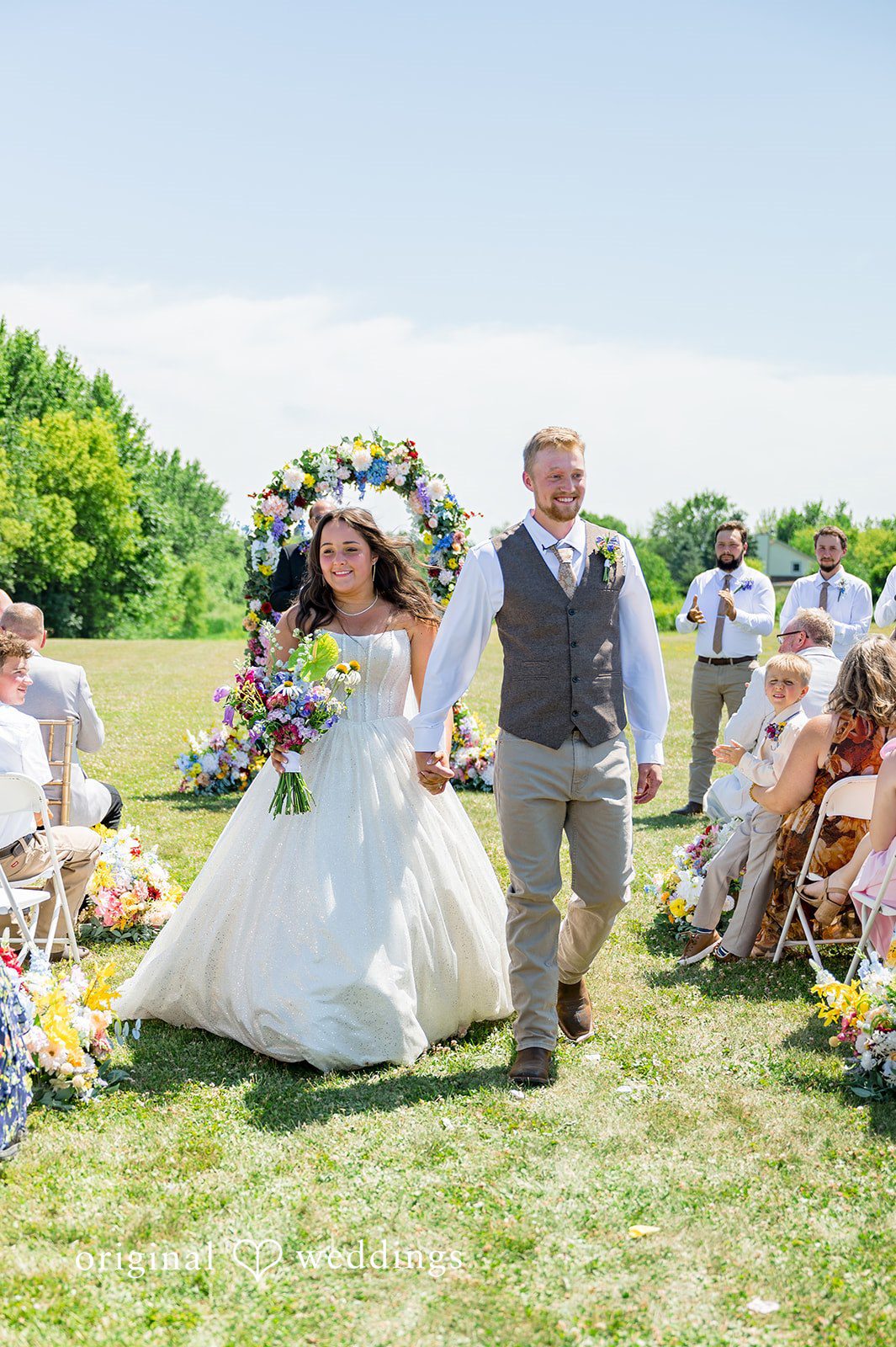 Melayna + Harley A bride and groom walk down the aisle together after their ceremony.