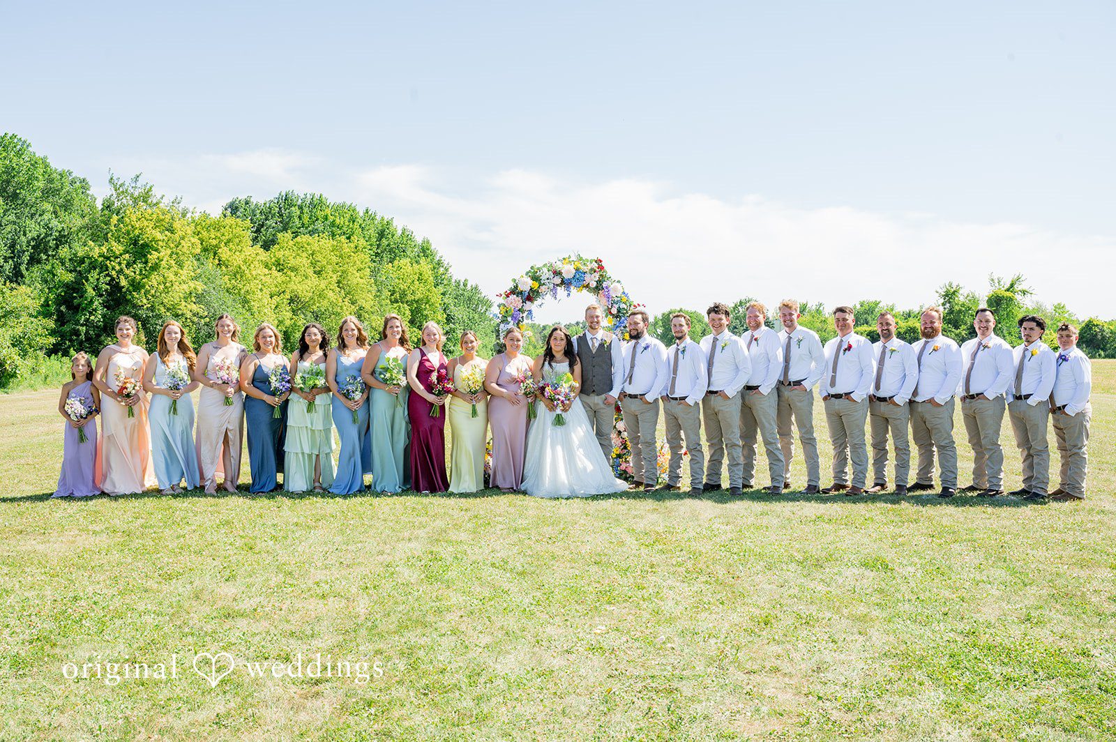 Melayna + Harley A large wedding party poses together on and around a red tractor.