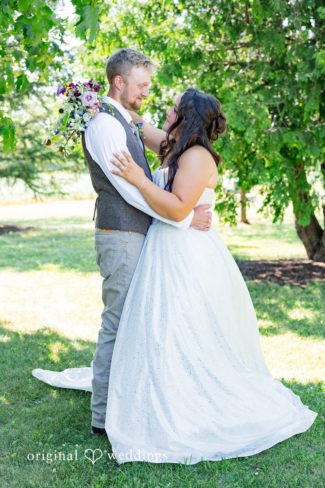 Melayna + Harley A groom holds his bride's hands as they pose under a tree canopy.