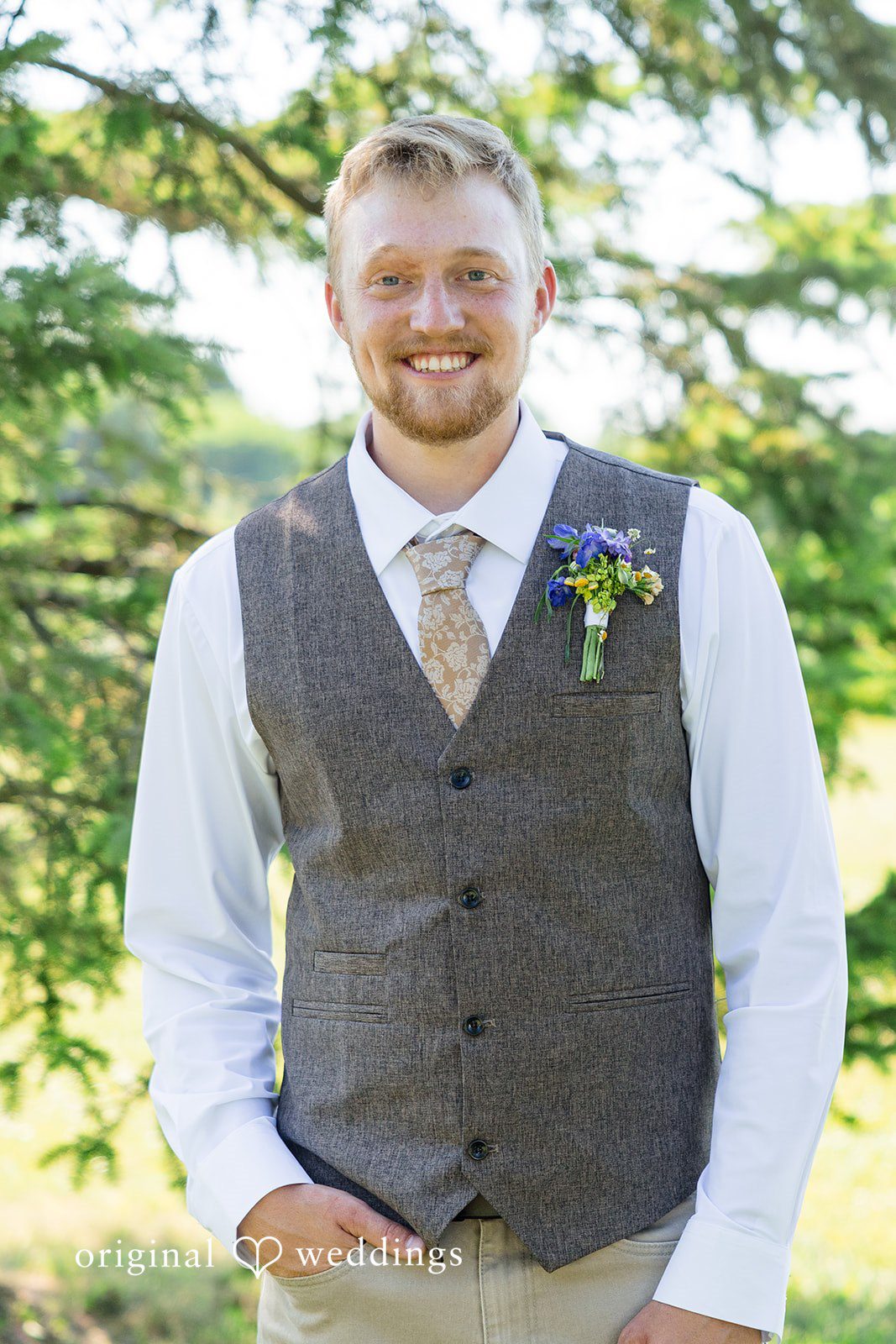 Melayna + Harley A groom in a grey vest smiles for a portrait.