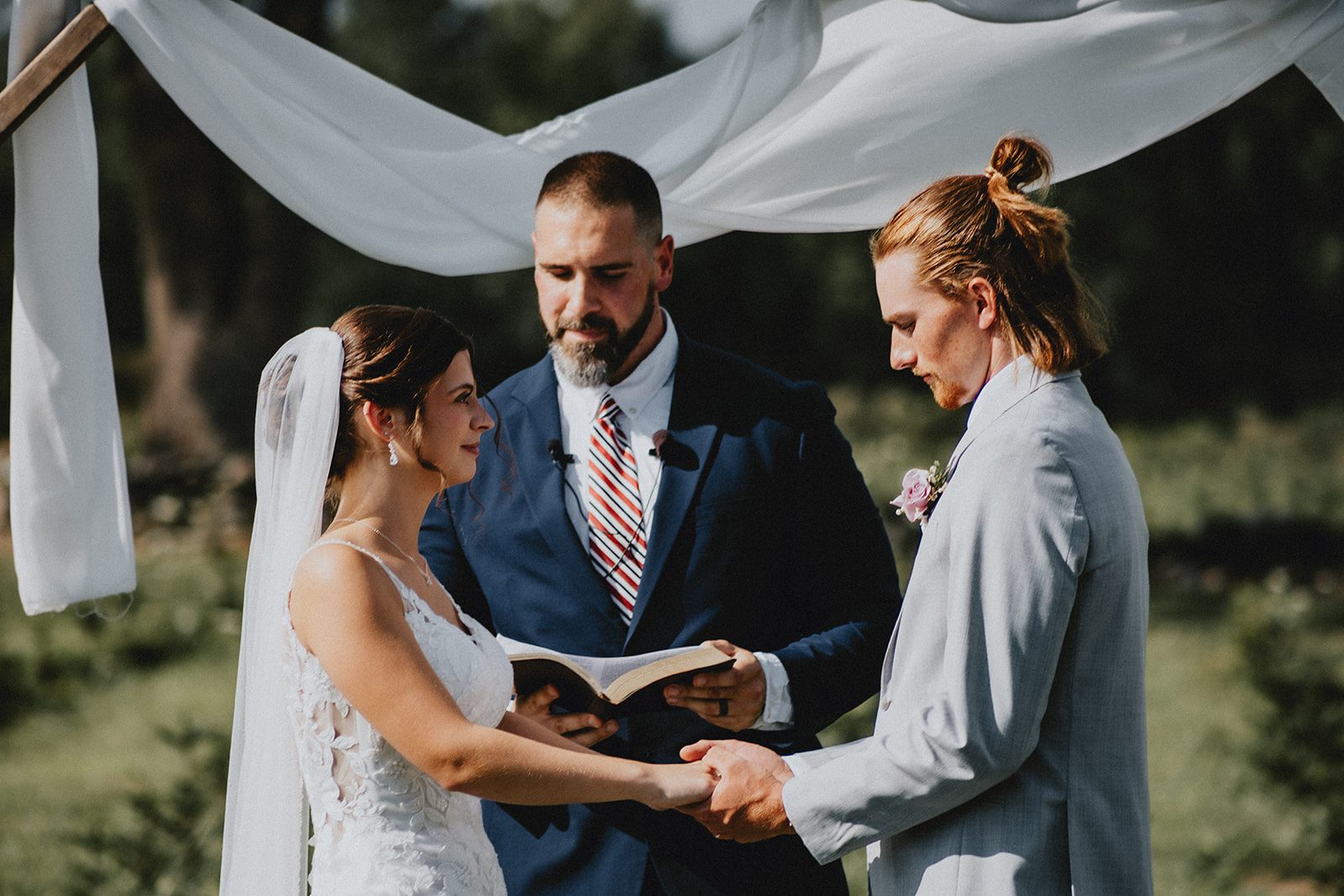 Couple sharing vows by the wooden arbor Couple sharing vows by the wooden arbor