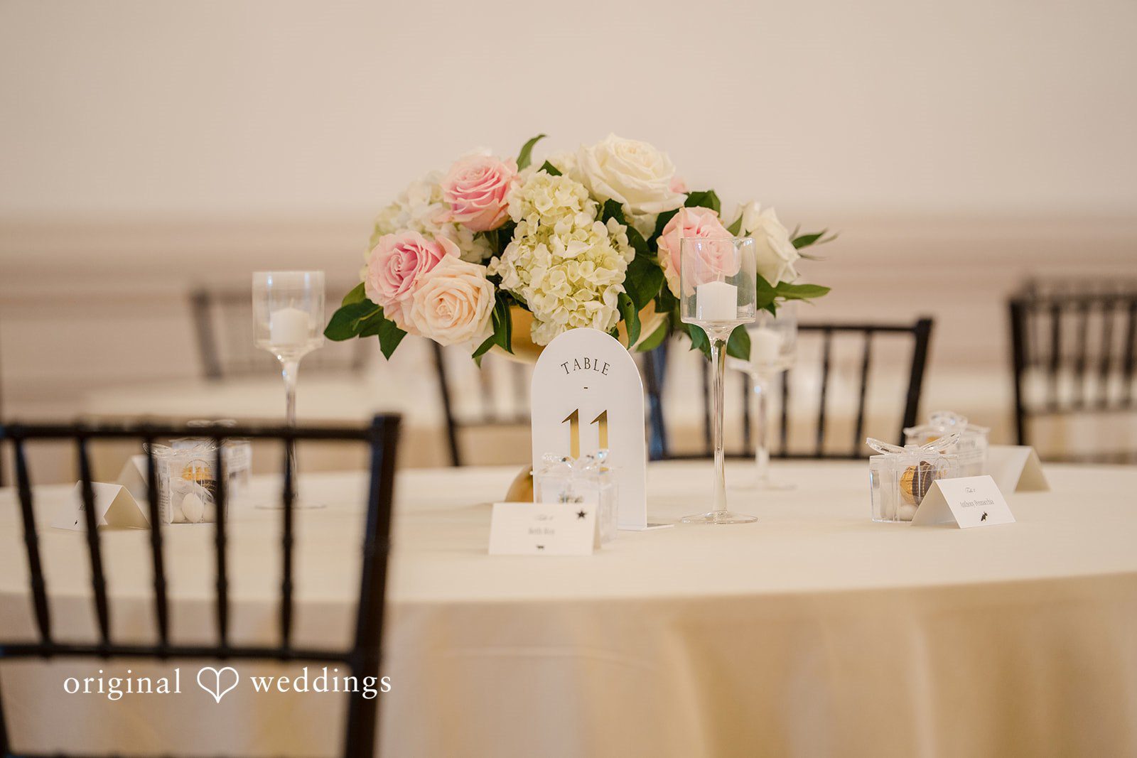 Emily + Angelo Table setting with a large pink and white floral centerpiece in a tall clear vase.
