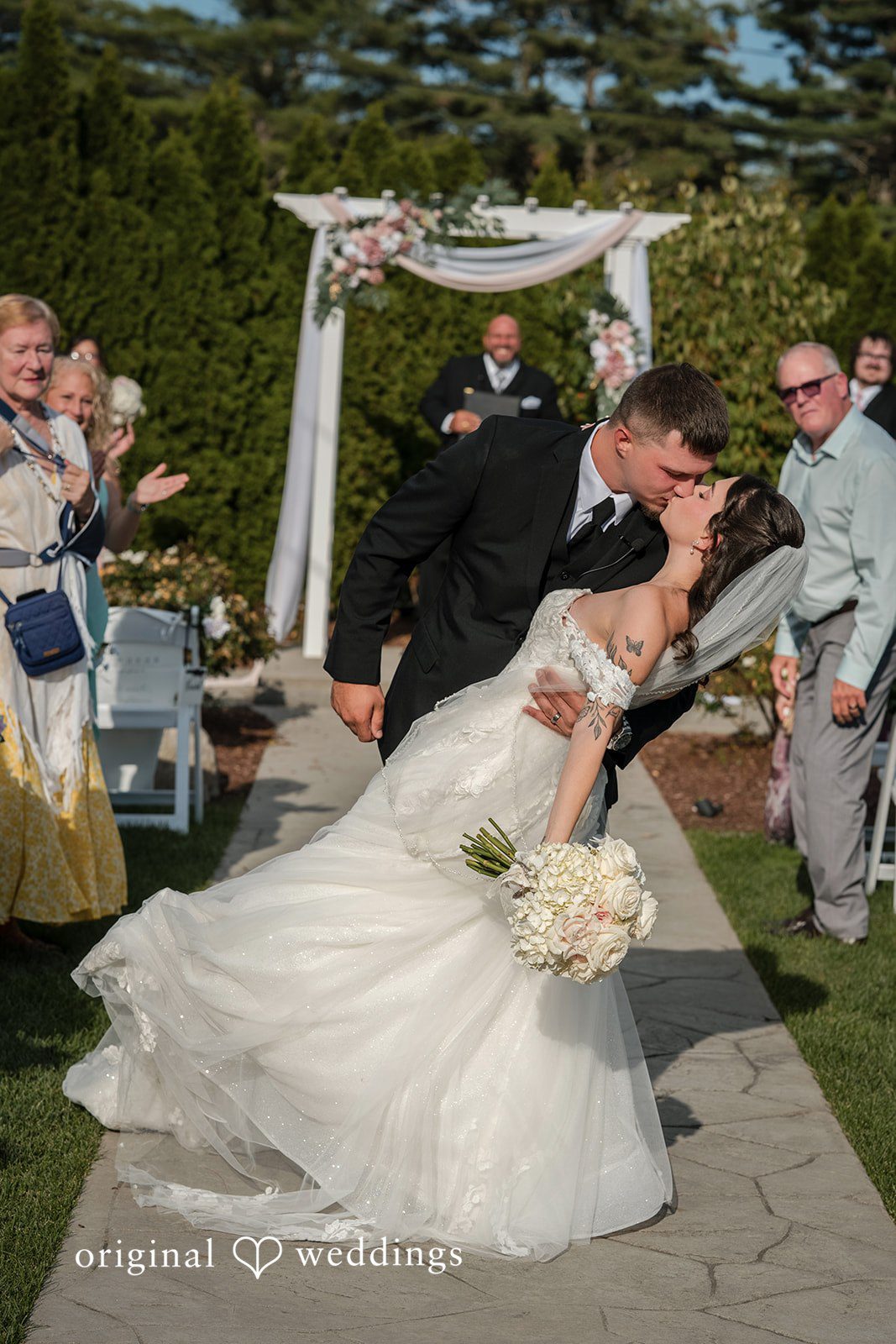 Emily + Angelo Bride and groom lying down together on a stone walkway with her dress train spread out.
