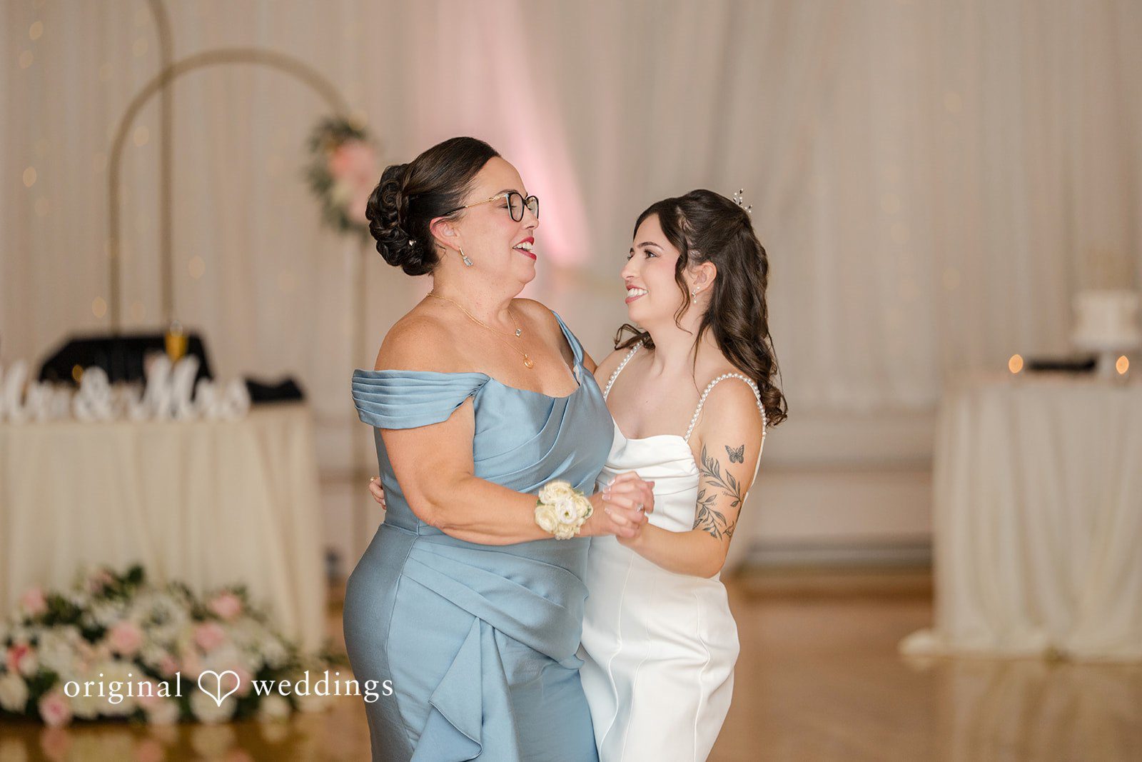 Emily + Angelo Bride and women in elegant dresses smiling and talking together at a reception.