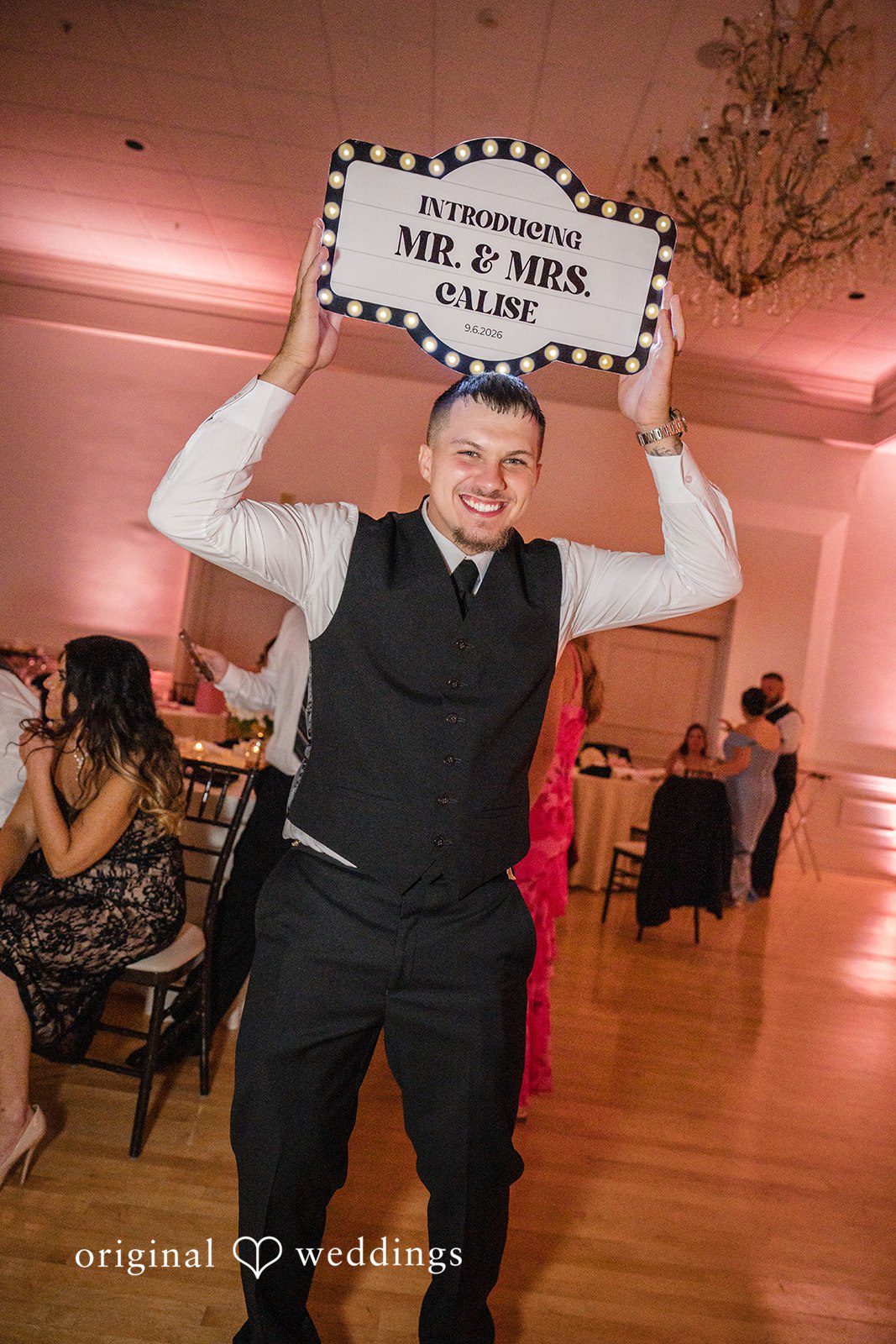 Emily + Angelo Groom holding up a fun wedding sign while dancing at the reception.