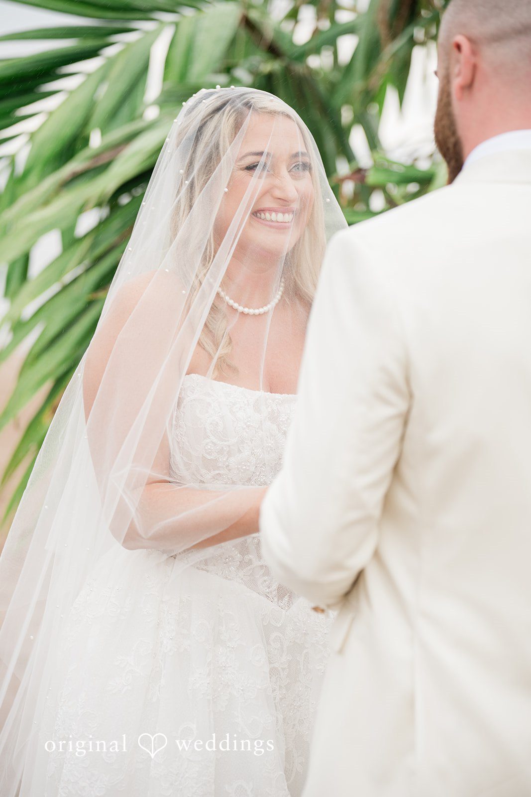 Jackie + Will Couple close together beside the palms
