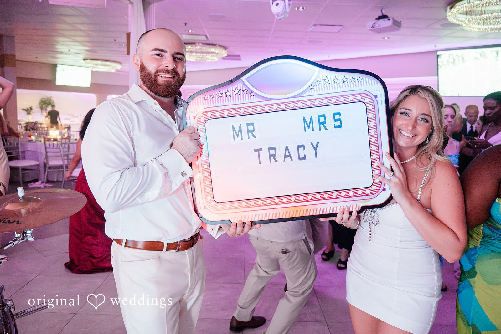 Jackie + Will Groom holding a light box sign at the reception