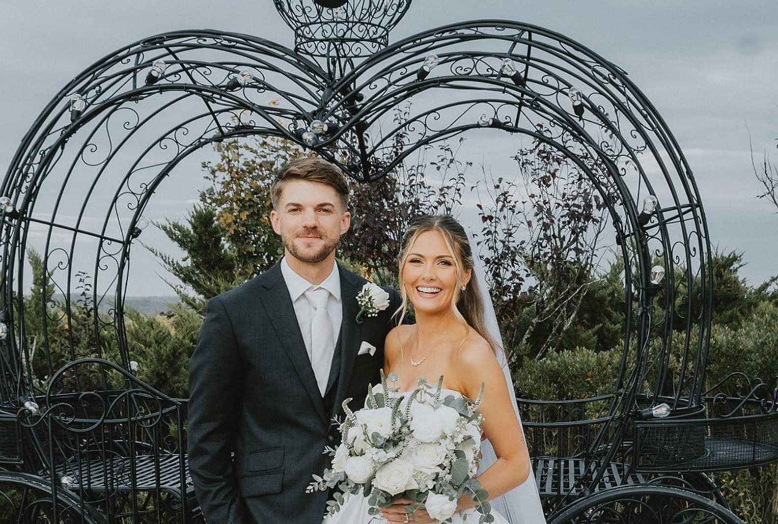Emily and Max in front of the iron carriage arch, captured by Hartford wedding photographers from Original Weddings at Aria Wedding and Banquet Facility