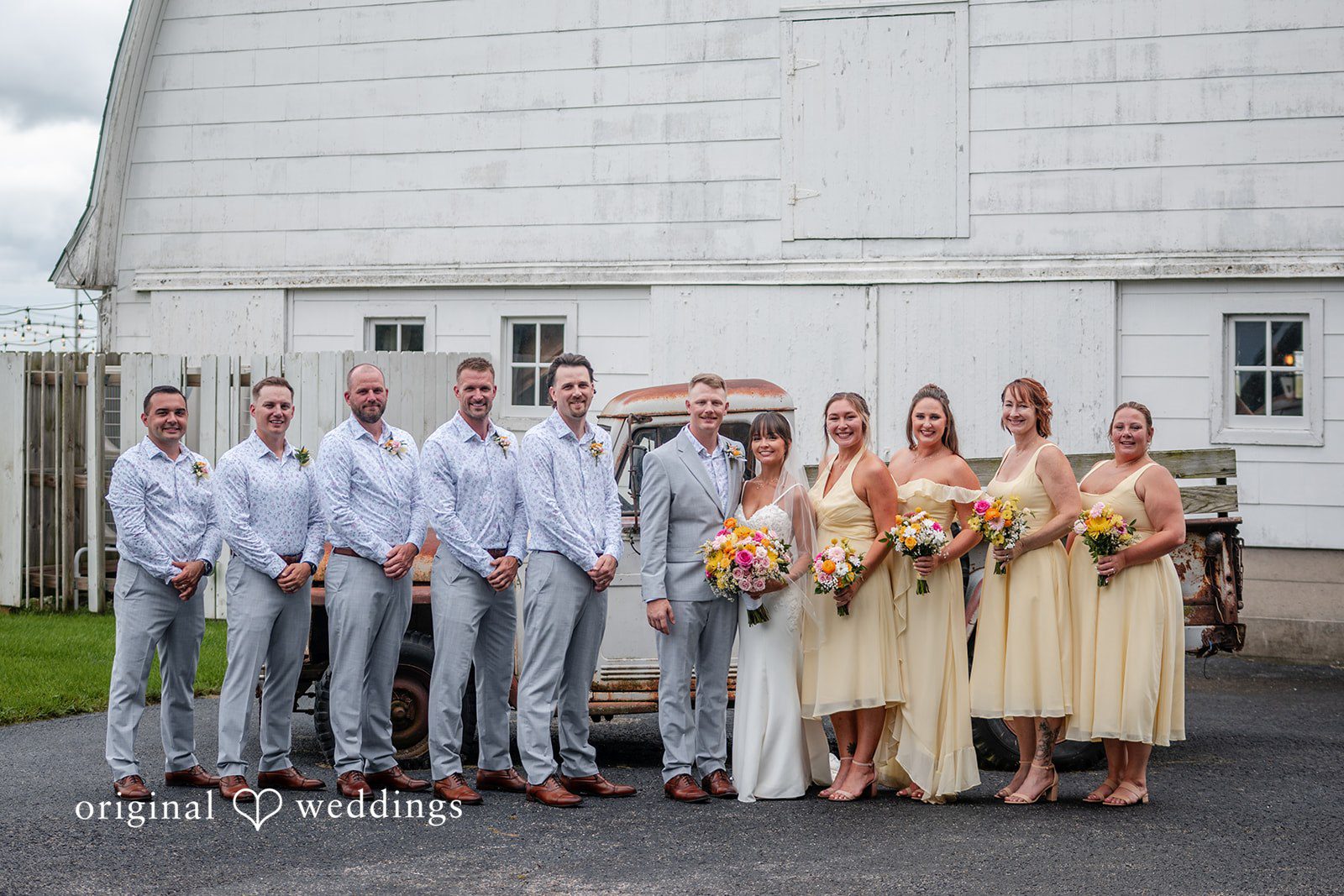 Wedding party lined up beside a white barn at Ashley Farm
