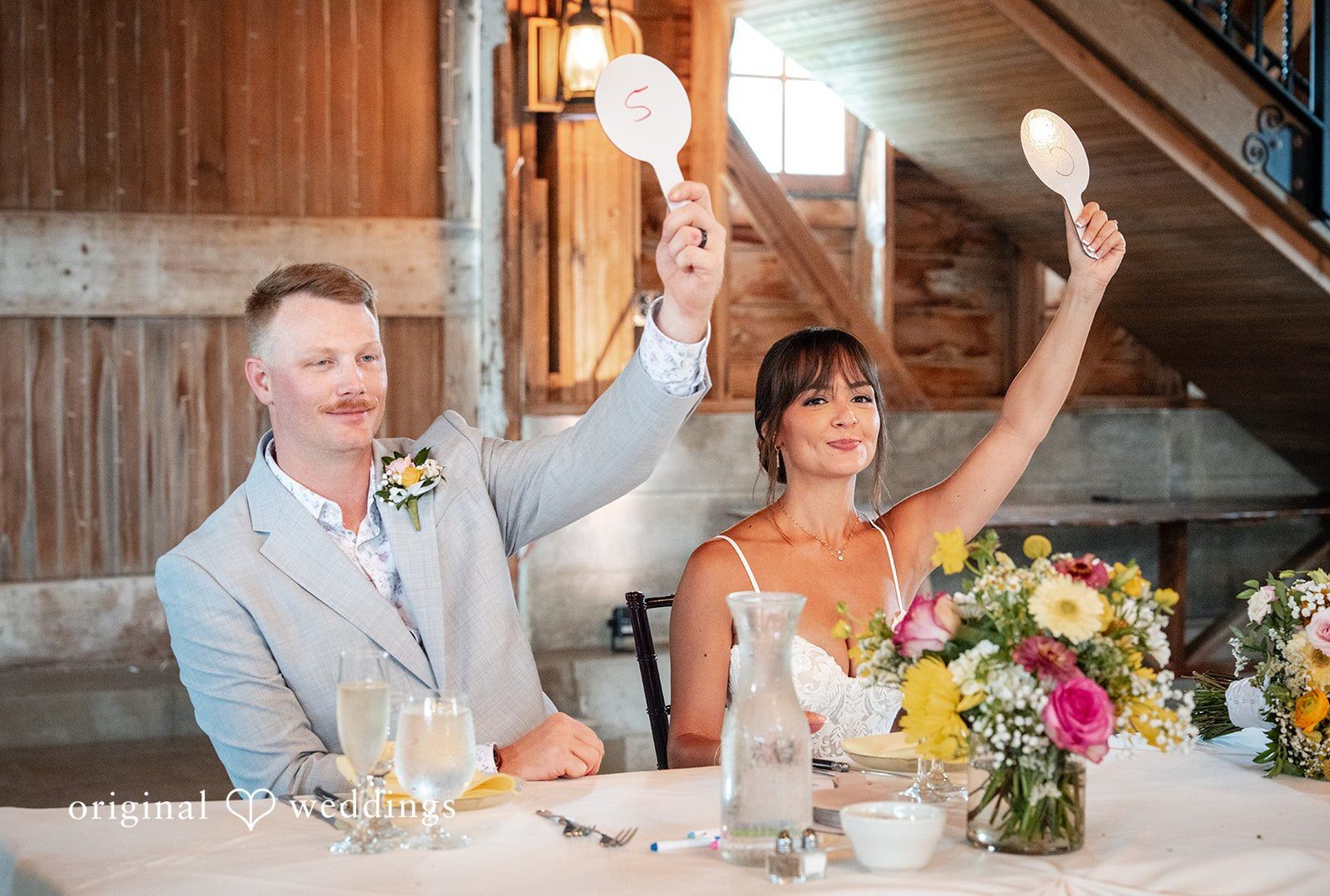 Couple cheering at their sweetheart table, captured by Chicago wedding photographers from Original Weddings at Ashley Farm