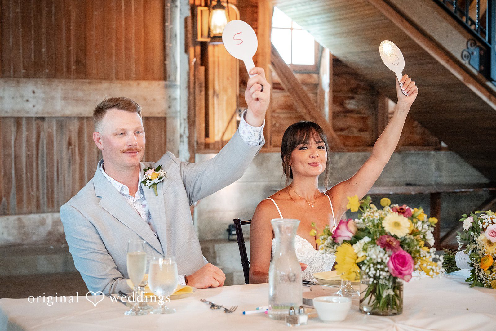 Couple cheering at their sweetheart table, captured by Chicago wedding photographers from Original Weddings at Ashley Farm