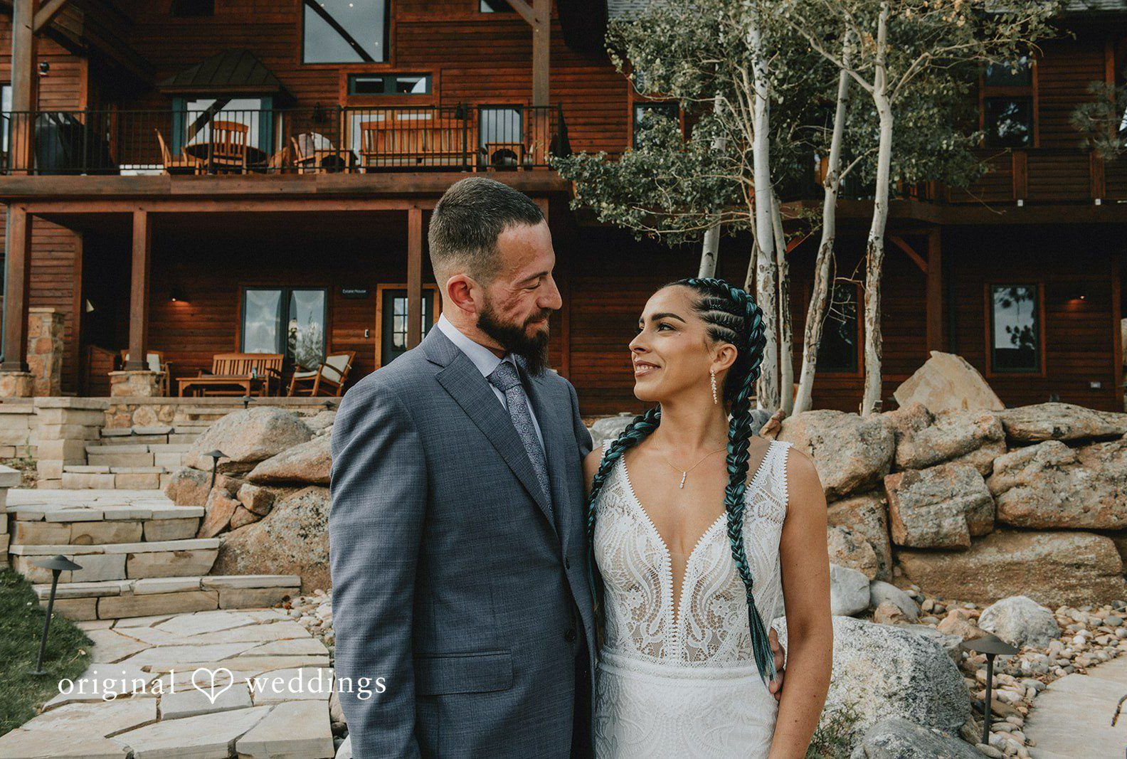 Johana and Arthur posing in front of the mountain lodge, captured by Denver wedding photographers from Original Weddings at Aspen Falls